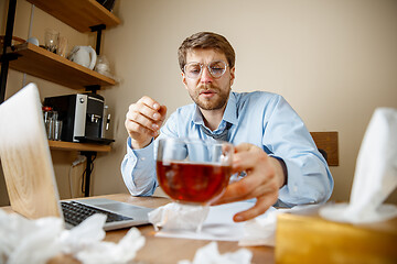 Image showing Sick man while working in office, businessman caught cold, seasonal flu.