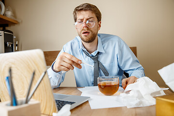 Image showing Sick man while working in office, businessman caught cold, seasonal flu.