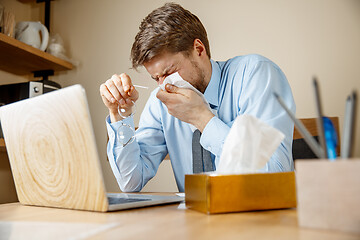 Image showing Sick man while working in office, businessman caught cold, seasonal flu.