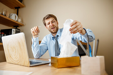 Image showing Sick man while working in office, businessman caught cold, seasonal flu.