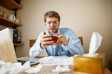 Image showing Sick man while working in office, businessman caught cold, seasonal flu.