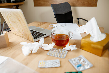 Image showing A cup of tea with pills, medicines, paper handkerchiefs at desk