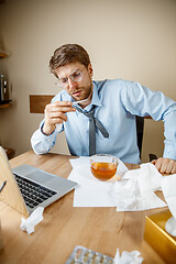 Image showing Sick man while working in office, businessman caught cold, seasonal flu.