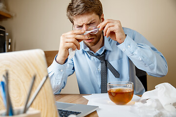 Image showing Sick man while working in office, businessman caught cold, seasonal flu.