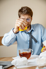 Image showing Sick man while working in office, businessman caught cold, seasonal flu.