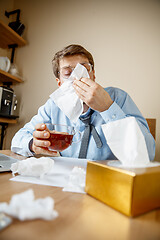 Image showing Sick man while working in office, businessman caught cold, seasonal flu.