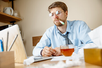 Image showing Sick man while working in office, businessman caught cold, seasonal flu.