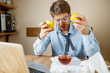 Image showing Sick man while working in office, businessman caught cold, seasonal flu.