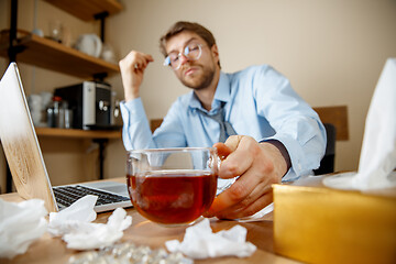 Image showing Sick man while working in office, businessman caught cold, seasonal flu.