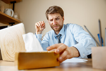 Image showing Sick man while working in office, businessman caught cold, seasonal flu.