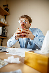 Image showing Sick man while working in office, businessman caught cold, seasonal flu.