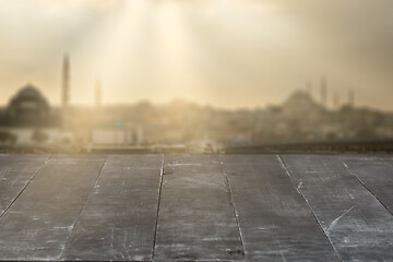 Image showing Old wooden dark grey table for display your products on a blurred cityscape background.