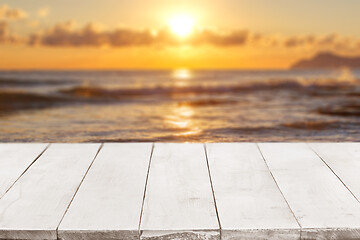 Image showing Empty white wooden boards or countertop against seascape with sunset on background. Template, mockup for display or montage of products. Close up