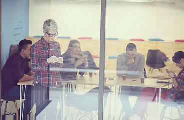 Image showing business woman at office speaking by phone  team on meeting in b