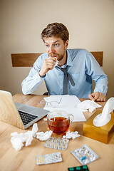 Image showing Sick man while working in office, businessman caught cold, seasonal flu.