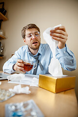 Image showing Sick man while working in office, businessman caught cold, seasonal flu.