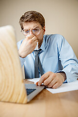 Image showing Sick man while working in office, businessman caught cold, seasonal flu.