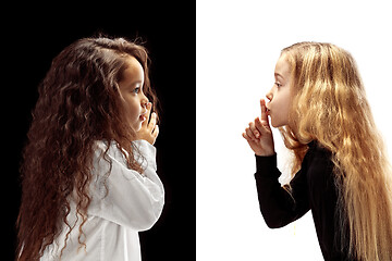 Image showing The young teen girls whispering a secret behind her hand over pink background