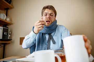 Image showing Sick man while working in office, businessman caught cold, seasonal flu.