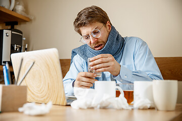 Image showing Sick man while working in office, businessman caught cold, seasonal flu.