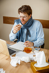 Image showing Sick man while working in office, businessman caught cold, seasonal flu.