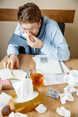 Image showing Sick man while working in office, businessman caught cold, seasonal flu.