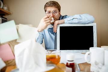 Image showing Sick man while working in office, businessman caught cold, seasonal flu.