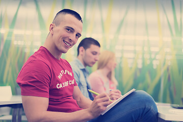 Image showing male student taking notes in classroom