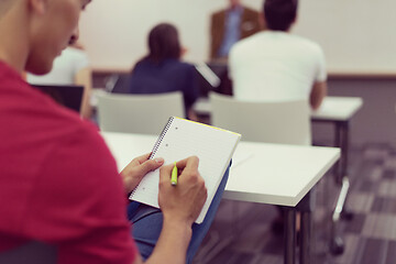 Image showing male student taking notes in classroom