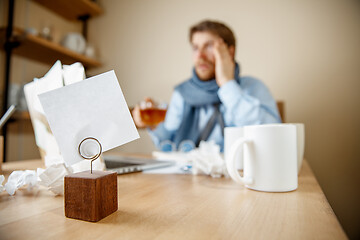 Image showing Feeling sick and tired. Frustrated young man massaging his head while sitting at his working place in office