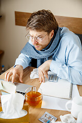 Image showing Sick man while working in office, businessman caught cold, seasonal flu.