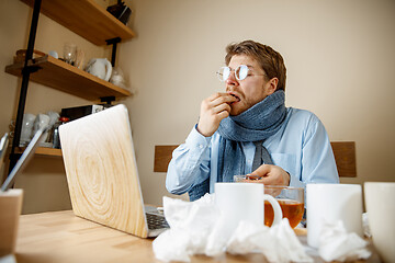 Image showing Sick man while working in office, businessman caught cold, seasonal flu.