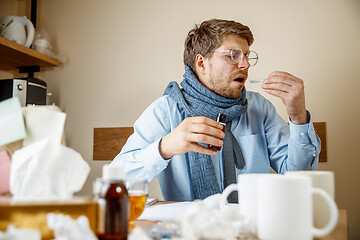 Image showing Sick man while working in office, businessman caught cold, seasonal flu.