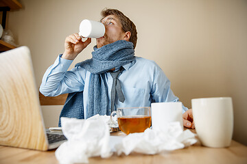 Image showing Sick man while working in office, businessman caught cold, seasonal flu.