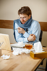 Image showing Sick man while working in office, businessman caught cold, seasonal flu.