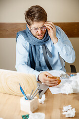 Image showing Feeling sick and tired. Frustrated young man massaging his head while sitting at his working place in office