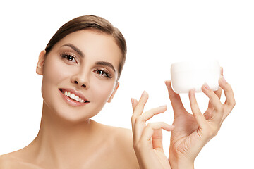 Image showing Cute girl preparing to start her day. She is applying moisturizer cream on face.