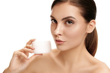 Image showing Cute girl preparing to start her day. She is applying moisturizer cream on face.