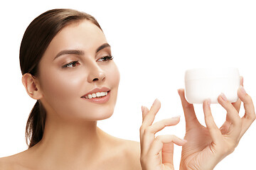 Image showing Cute girl preparing to start her day. She is applying moisturizer cream on face.