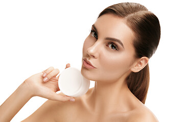 Image showing Cute girl preparing to start her day. She is applying moisturizer cream on face.