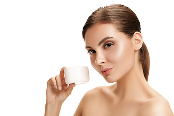 Image showing Cute girl preparing to start her day. She is applying moisturizer cream on face.