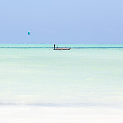 Image showing fishing boat and a kite surfer on picture perfect white sandy beach with turquoise blue sea, Paje, Zanzibar, Tanzania.