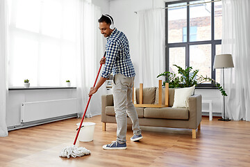 Image showing man in headphones with mop cleaning floor at home