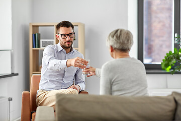 Image showing psychologist giving glass of water to senior woman