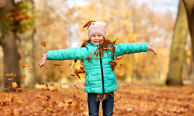 Image showing happy girl playing with leaves at autumn park