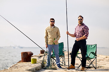 Image showing happy friends with fishing rods and beer on pier