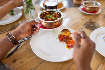 Image showing african man eating with friends at restaurant