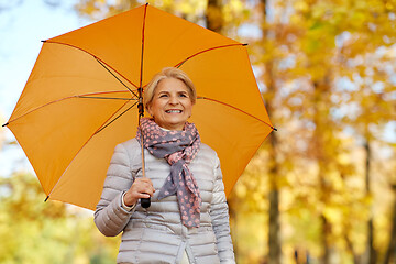 Image showing happy senior woman with umbrella at autumn park