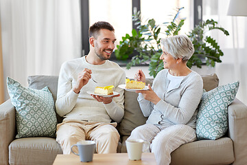 Image showing senior mother and adult son eating cake at home