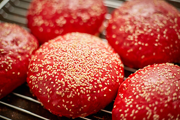 Image showing Fresh baked red homemade burger buns with sesame top view. Placed on metal grill.